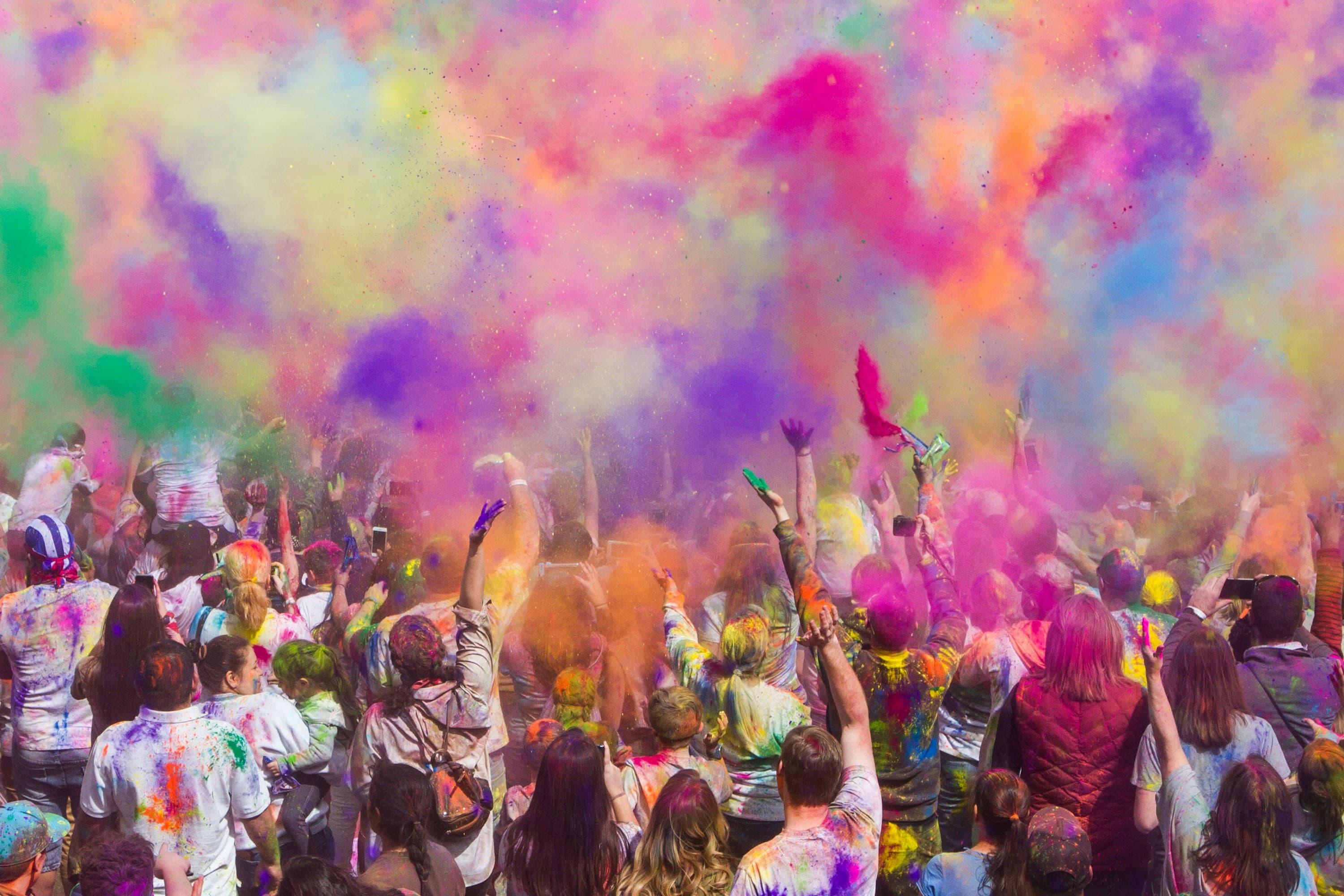 A crowd throwing colourful powder during a festival